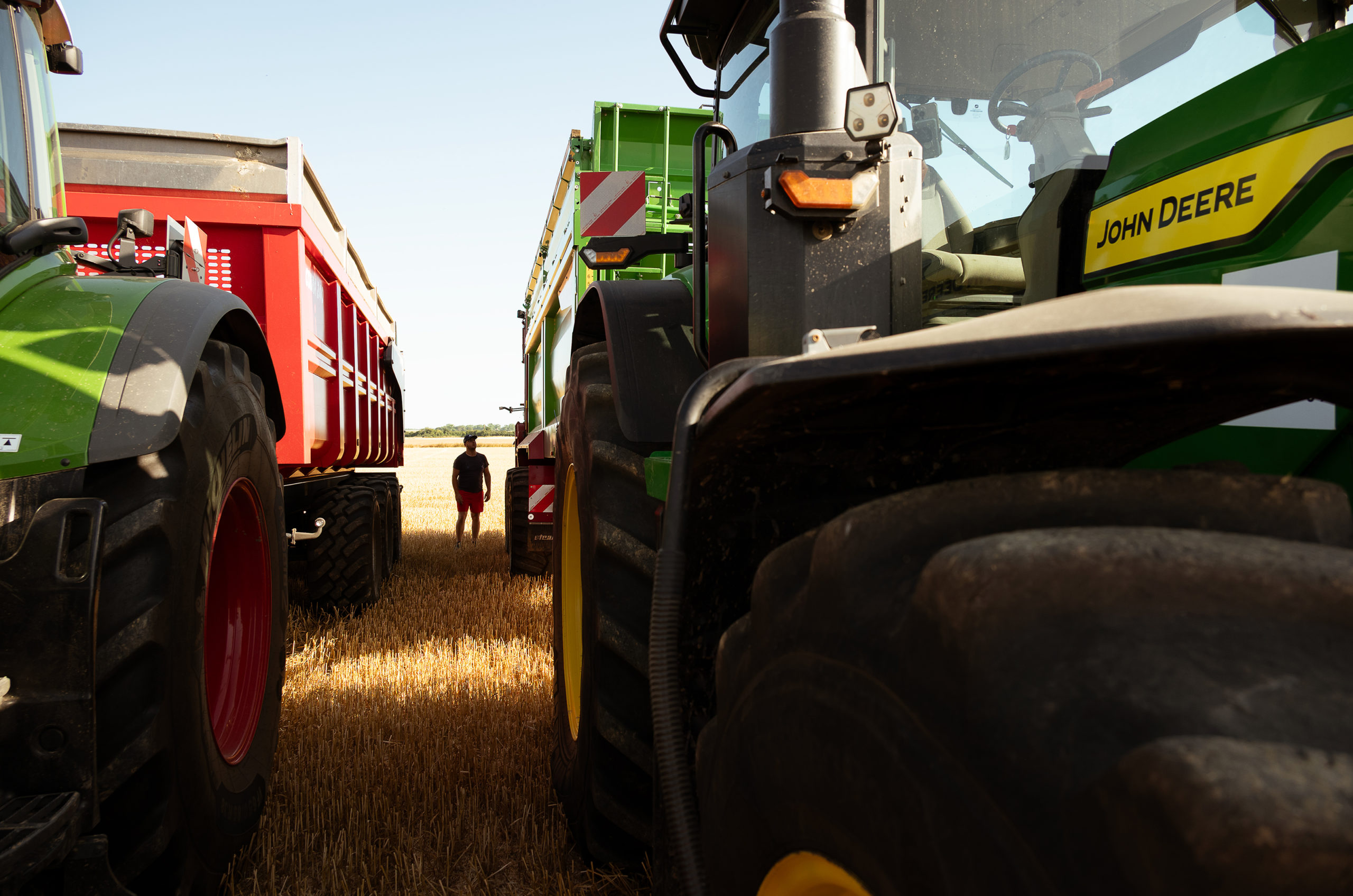 Un tracteur John Deere 7R 290 à côté d'un autre tracteur